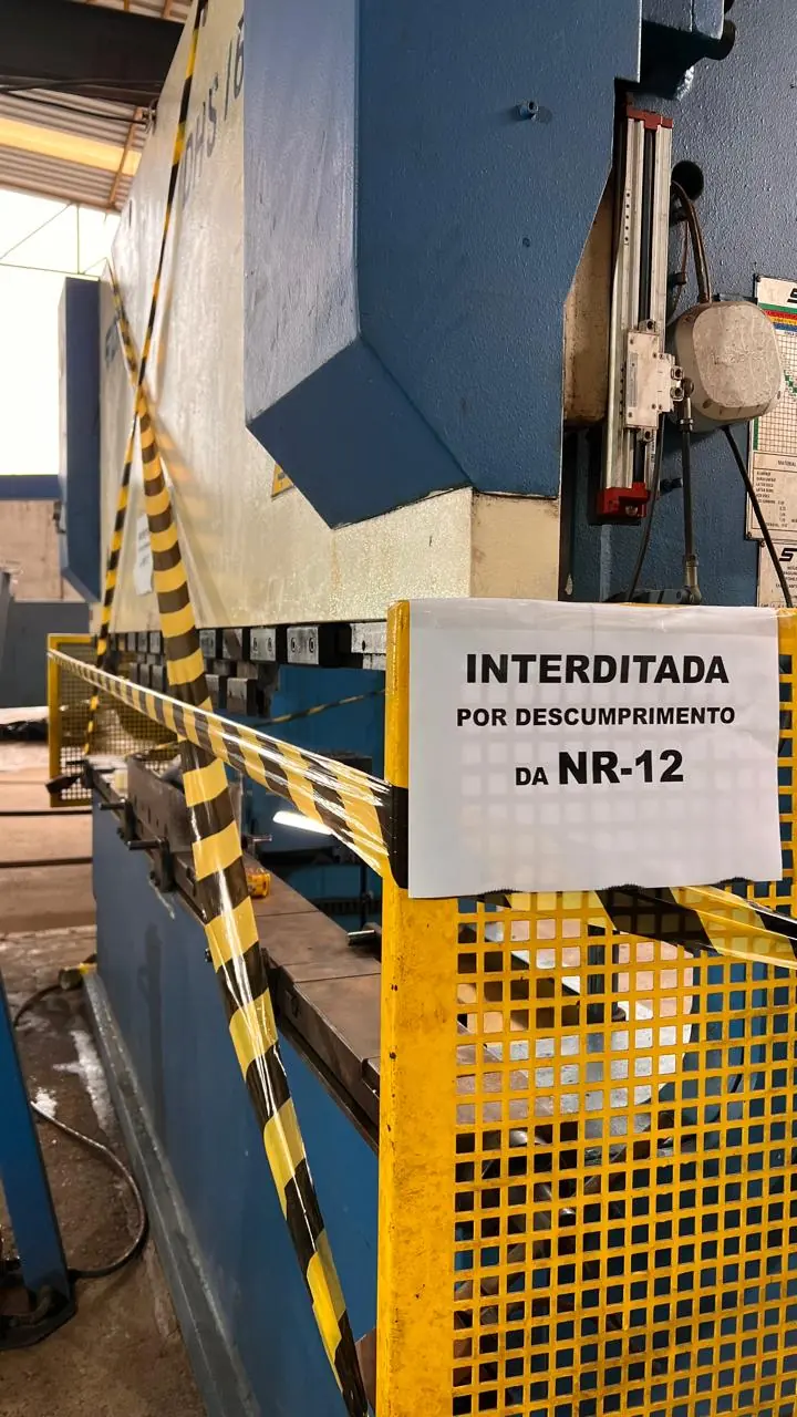 Dobradeira isolada com fita zebrada e aviso de interdição por descumprimento da NR-12